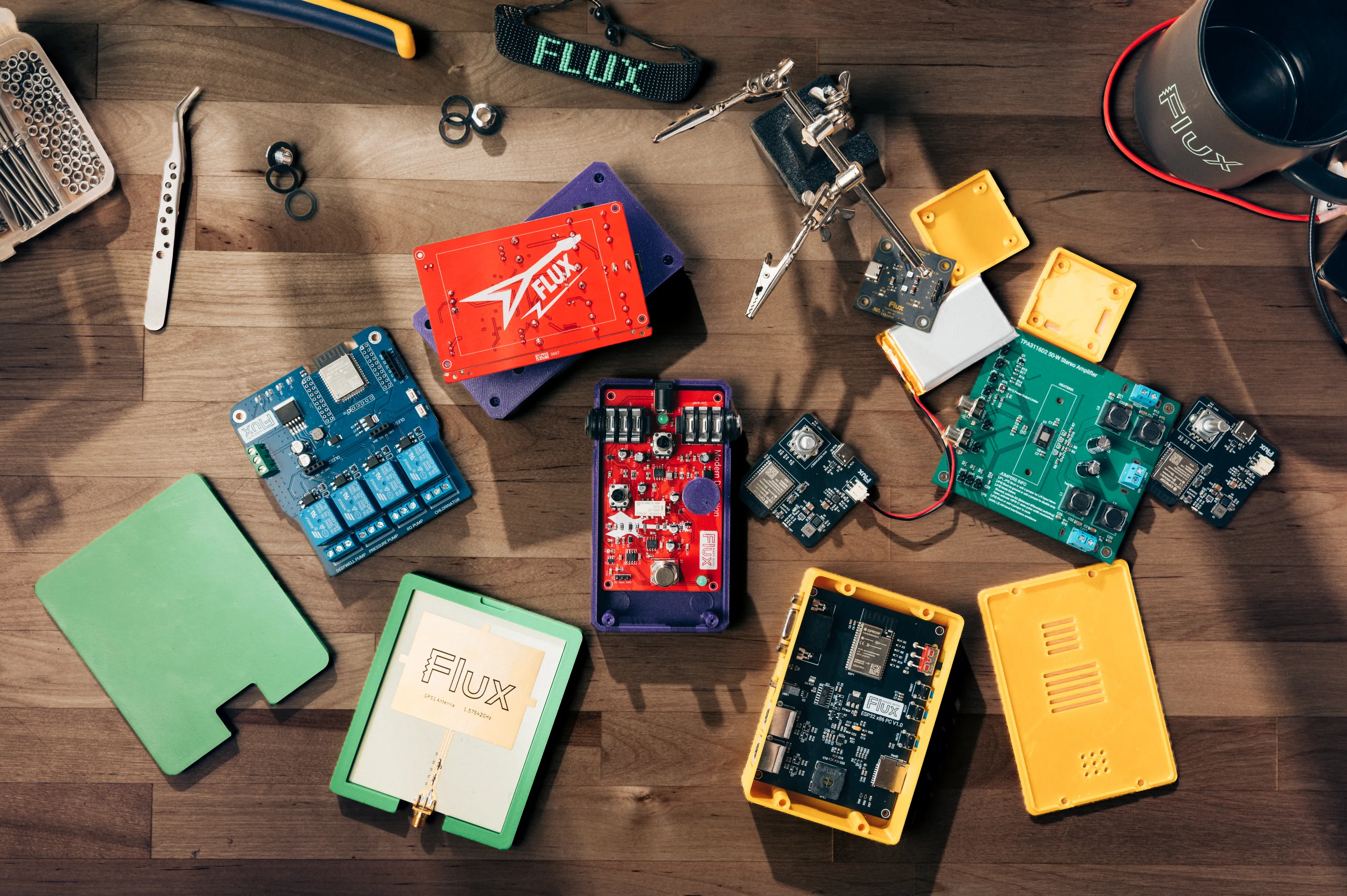 A flat lay of Flux circuit boards and colored 3D-printed enclosures on a workbench