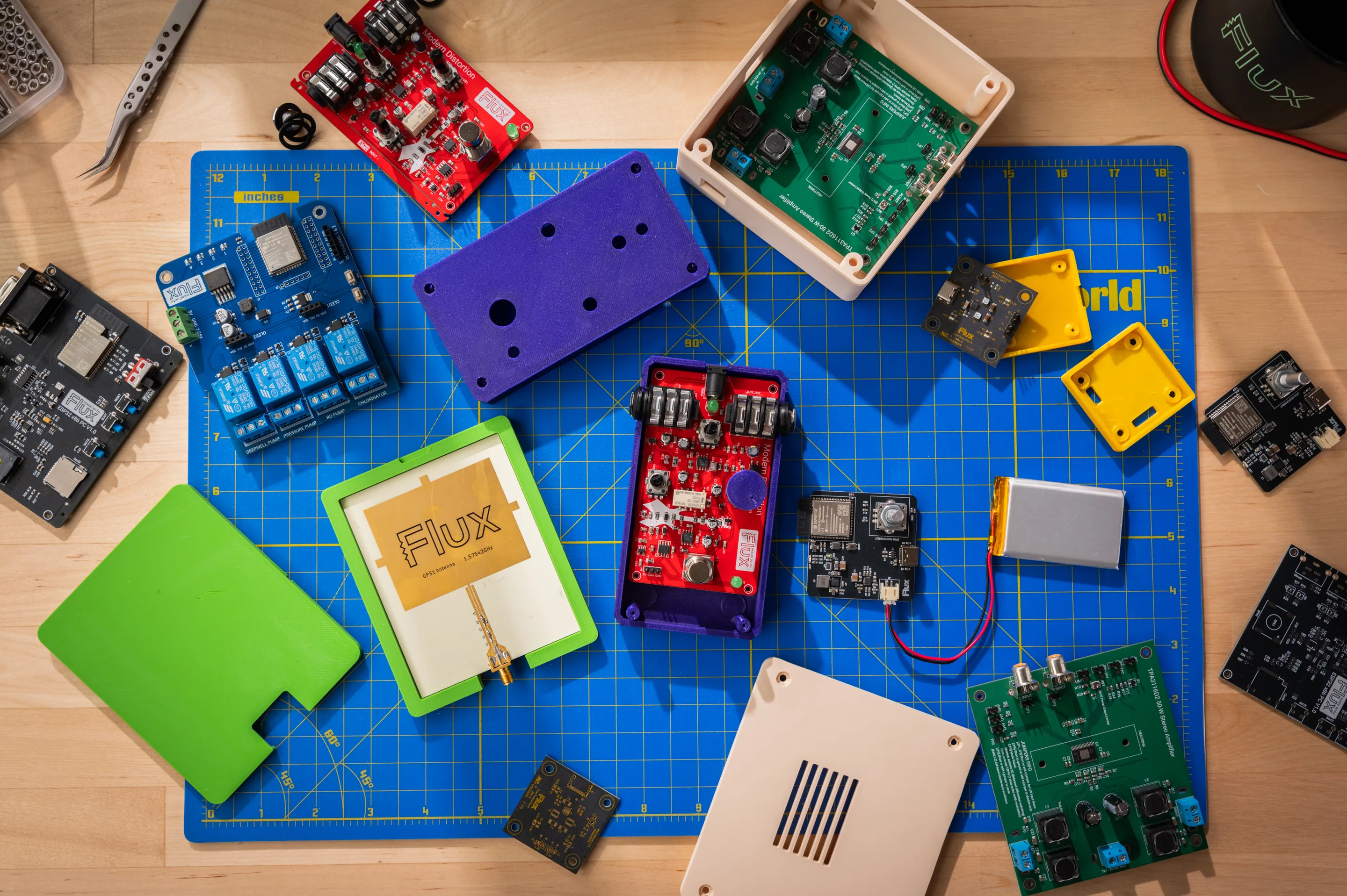 A flat lay of Flux circuit boards and colored enclosures on a workbench